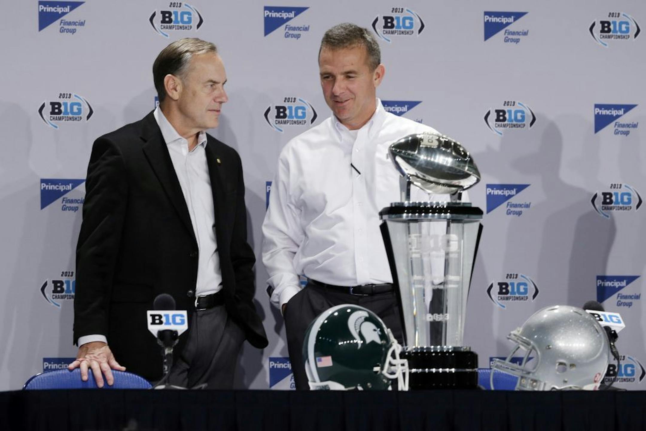 Michigan State head coach Mark Dantonio, left, talks with Ohio State head coach Urban Meyer during a news conference for the Big Ten Conference championship NCAA college football game Friday, Dec. 6, 2013, in Indianapolis. Ohio State will play Michigan State, Saturday for the championship.