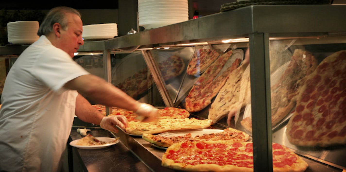 Andrea Gambinio, owner of Andrea PIzza in the skyway in the LaSalle Plaza works the counter where he serves the pizza slices. It's a family affair as his wife and two sons work the store as well.