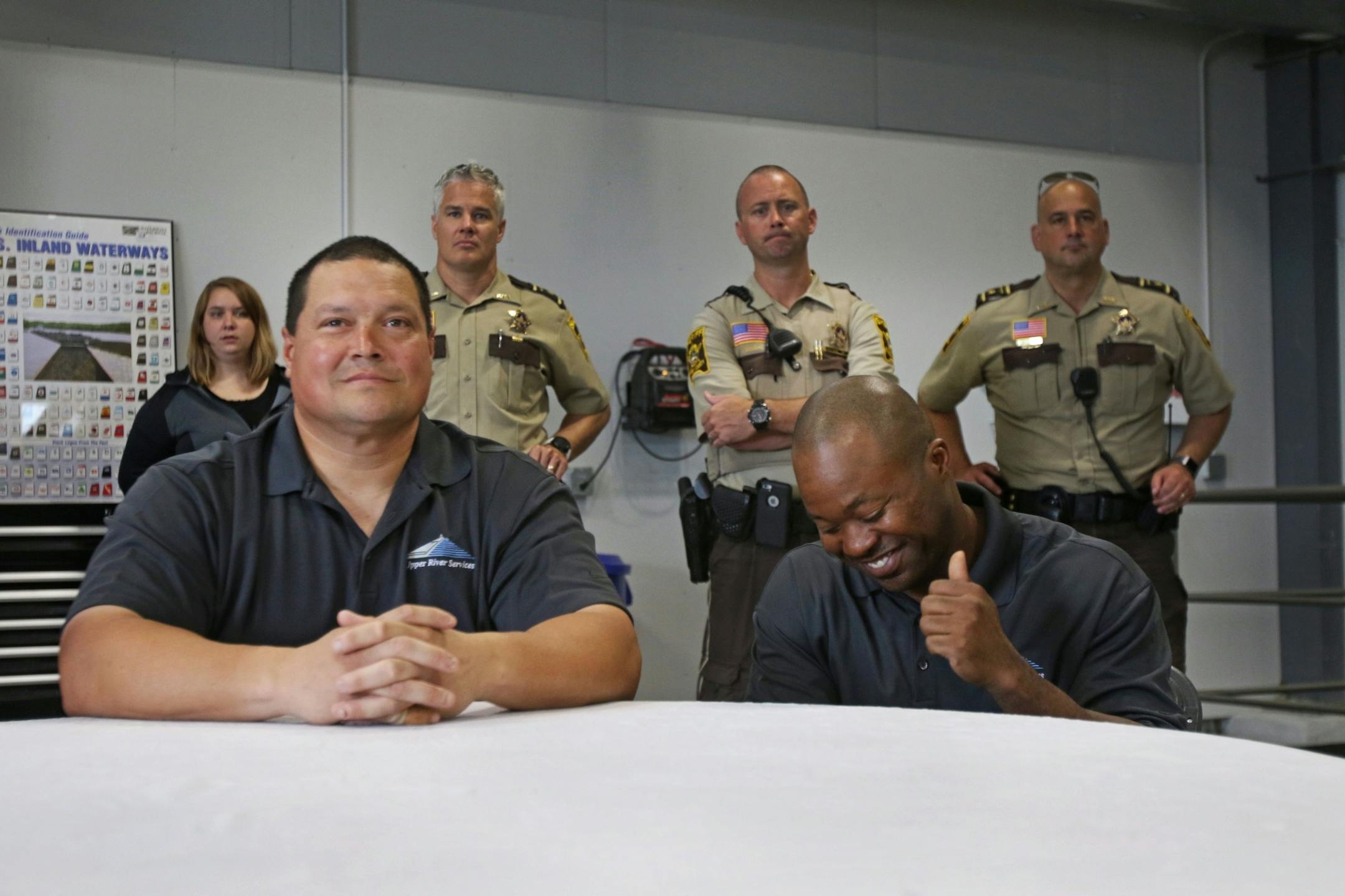 Beasley Baker (front right) gestured in excitement as he was recognized as the man who spotted the individual floating down the river. Russ Galvan (front left) later pulled the individual from the water. Both were honored along with three other workers at an award ceremony on Tuesday.