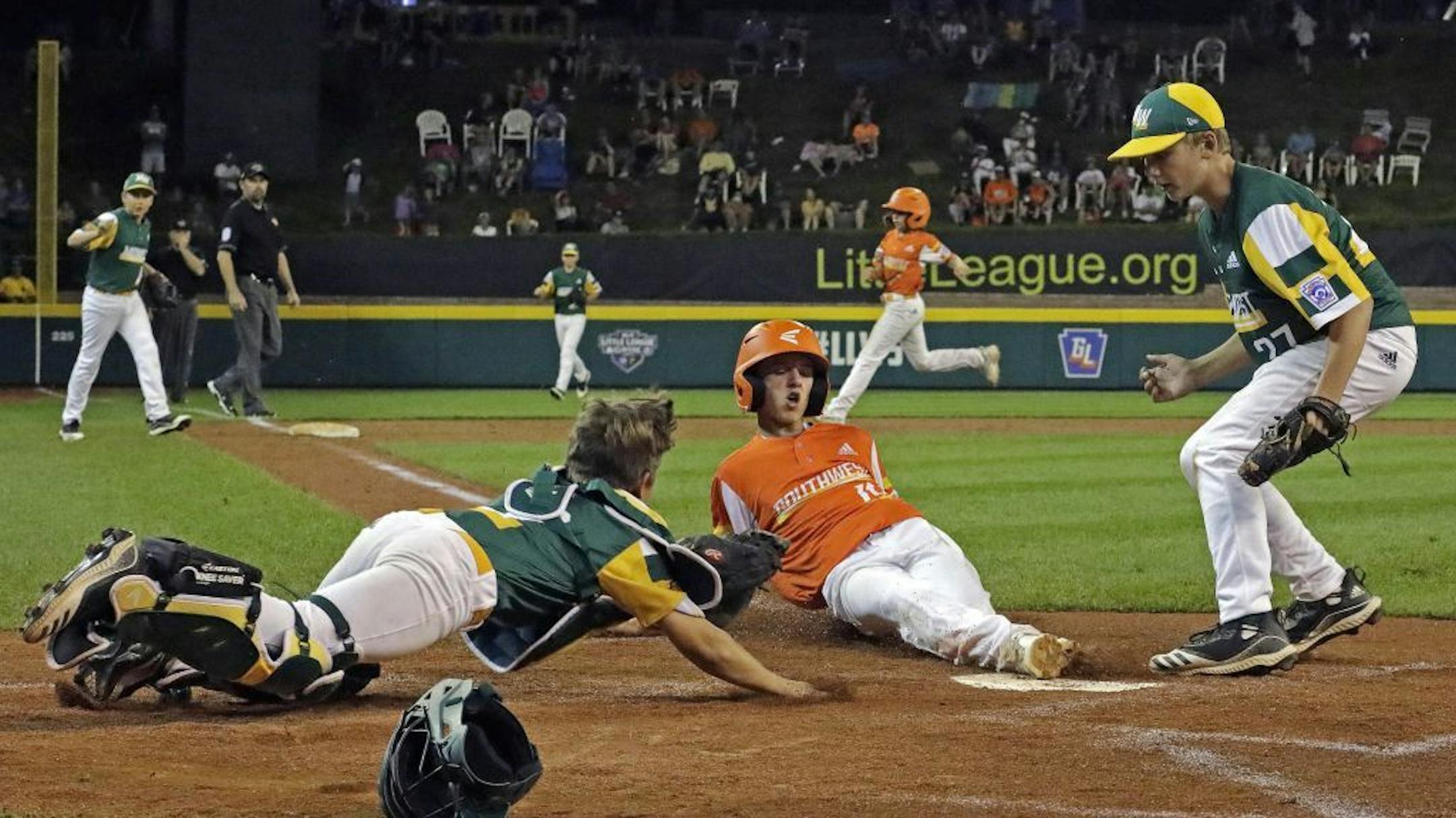 River Ridge, Louisiana's Gavin Berry, center, scores before Coon Rapids, Minnesota catcher Jameson Kuznia, left, can make the tag with Brett Buettner covering on a wild pitch during the fourth inning of an elimination baseball game at the Little League World Series tournament in South Williamsport, Pa., Monday, Aug. 19, 2019. Louisiana won 10-0.