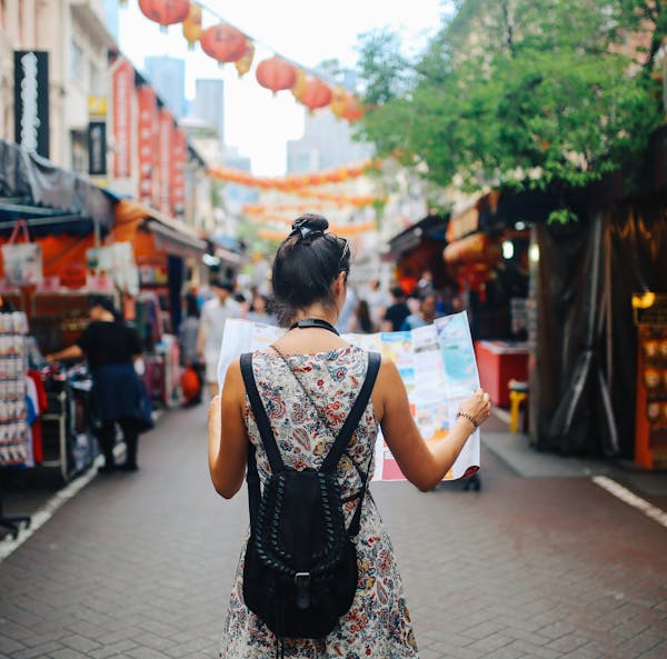 Rear view image of a young brunette woman. She is enjoying the walk and exploring the city, wearing a casual but fashionable dress, sightseeing and sh