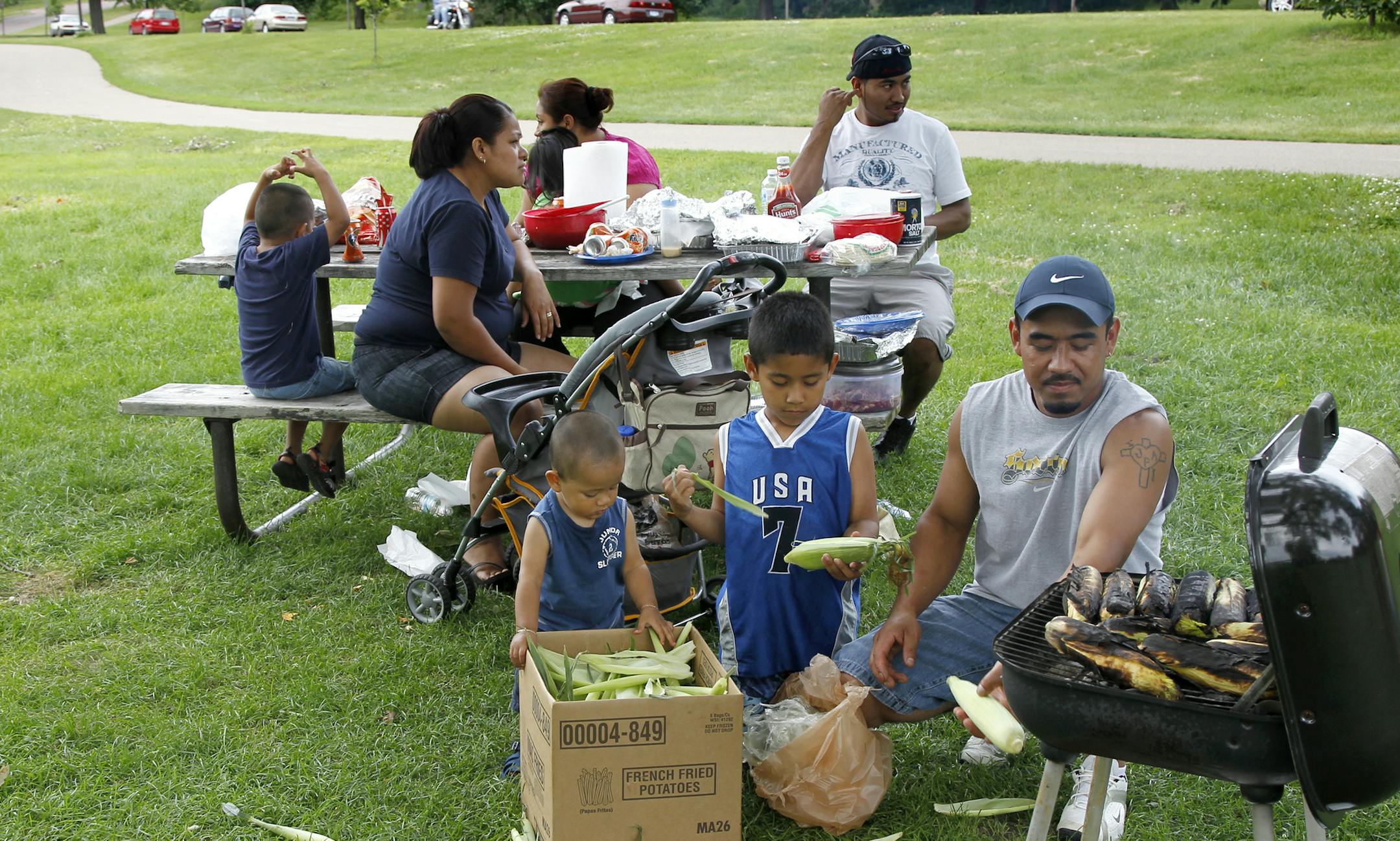 Jorge Ariza prepares roasted sweet corn with kids, left, David Ariza and Jorge J. Ariza for the picnic he and his family were having last week on the east shores of Lake Nokomis in south Minneapolis, MN. ] TOM WALLACE ‚Ä¢ twallace@startribune.com __Assignments #20018793A_ July 12, 2011_ SLUG: lake0723_ EXTRA INFORMATION : CQ by family, Jorge Ariza, David Ariza Jorge J. Ariza ORG XMIT: MIN2014040818392090