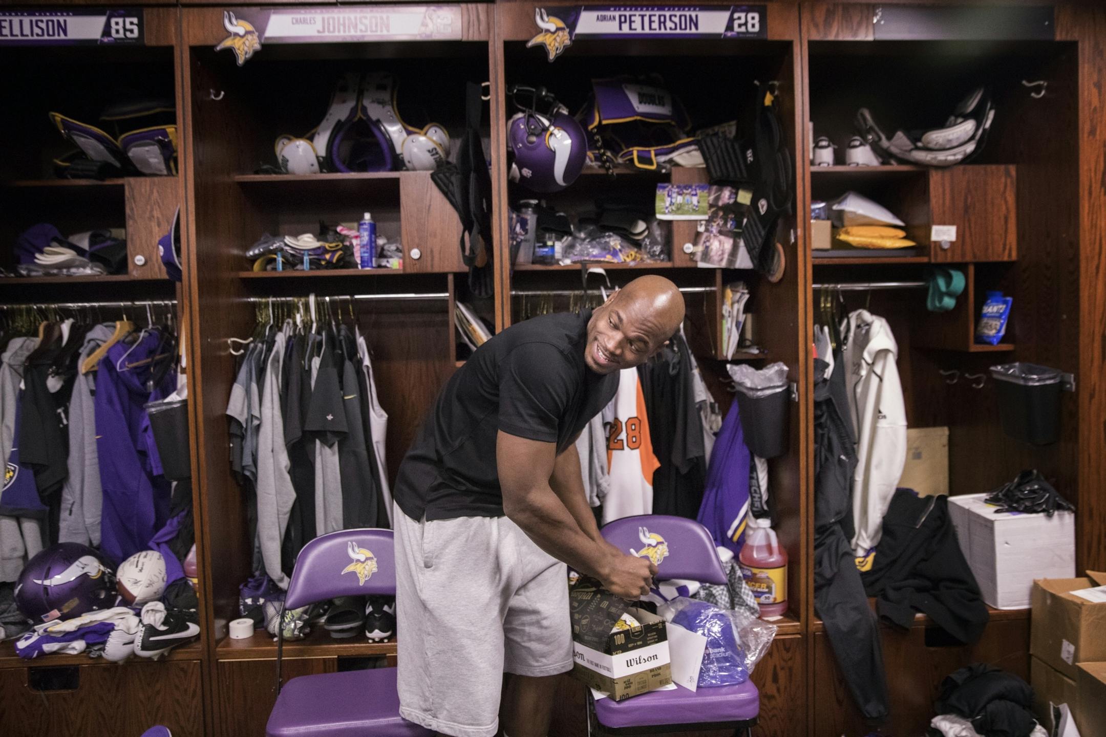Adrian Peterson signs a football at his locker.