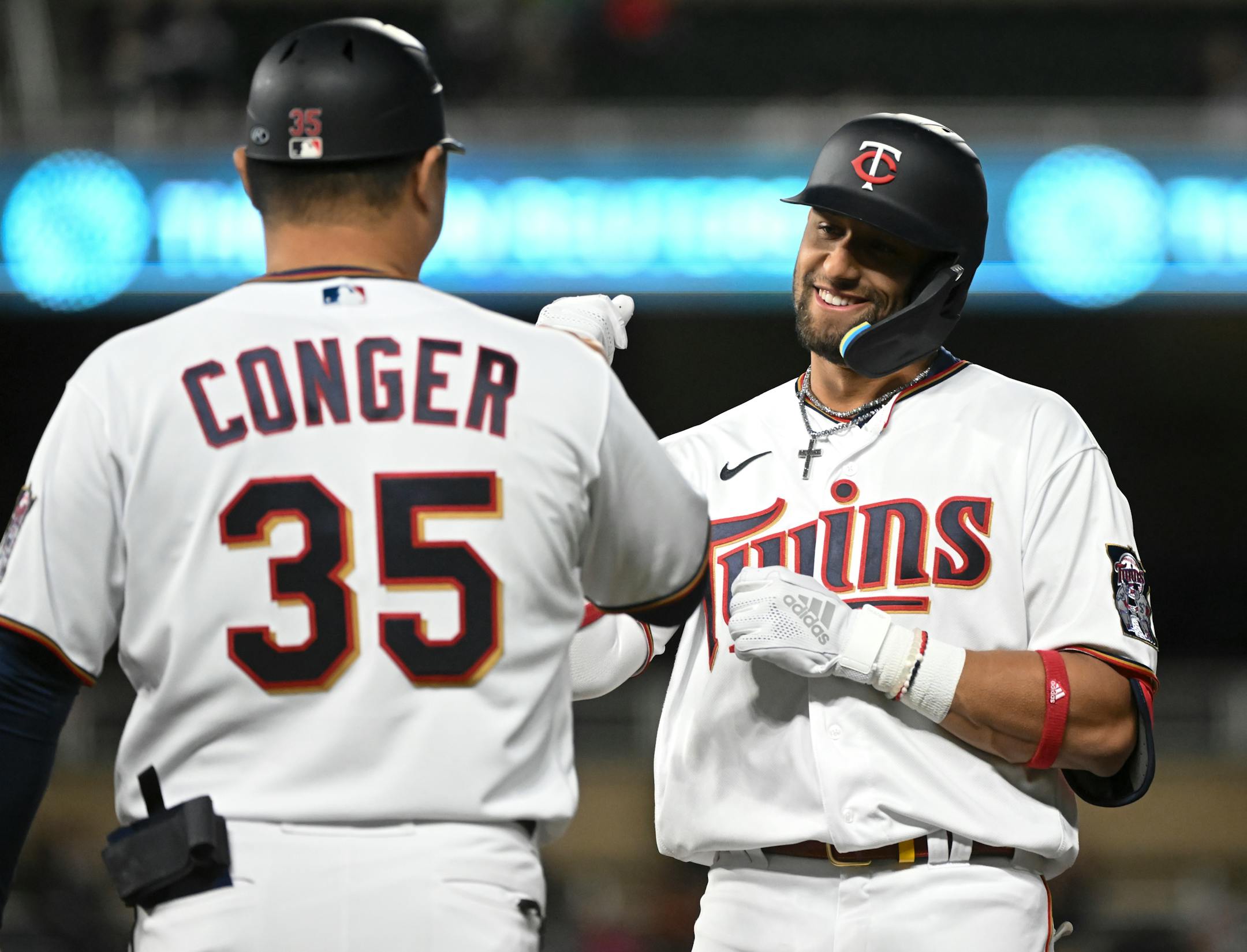 Minnesota Twins shortstop Royce Lewis (23) celebrates his first base hit with first base coach Hank Conger (35) in the bottom of the 8th inning.
