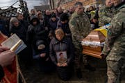 Relatives and friends mourn the body of senior police sergeant Roman Rushchyshyn in the village of Soposhyn, outskirts of Lviv, western Ukraine, Thurs