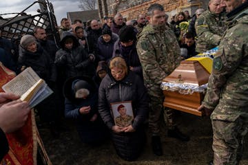 Relatives and friends mourn the body of senior police sergeant Roman Rushchyshyn in the village of Soposhyn, outskirts of Lviv, western Ukraine, Thurs