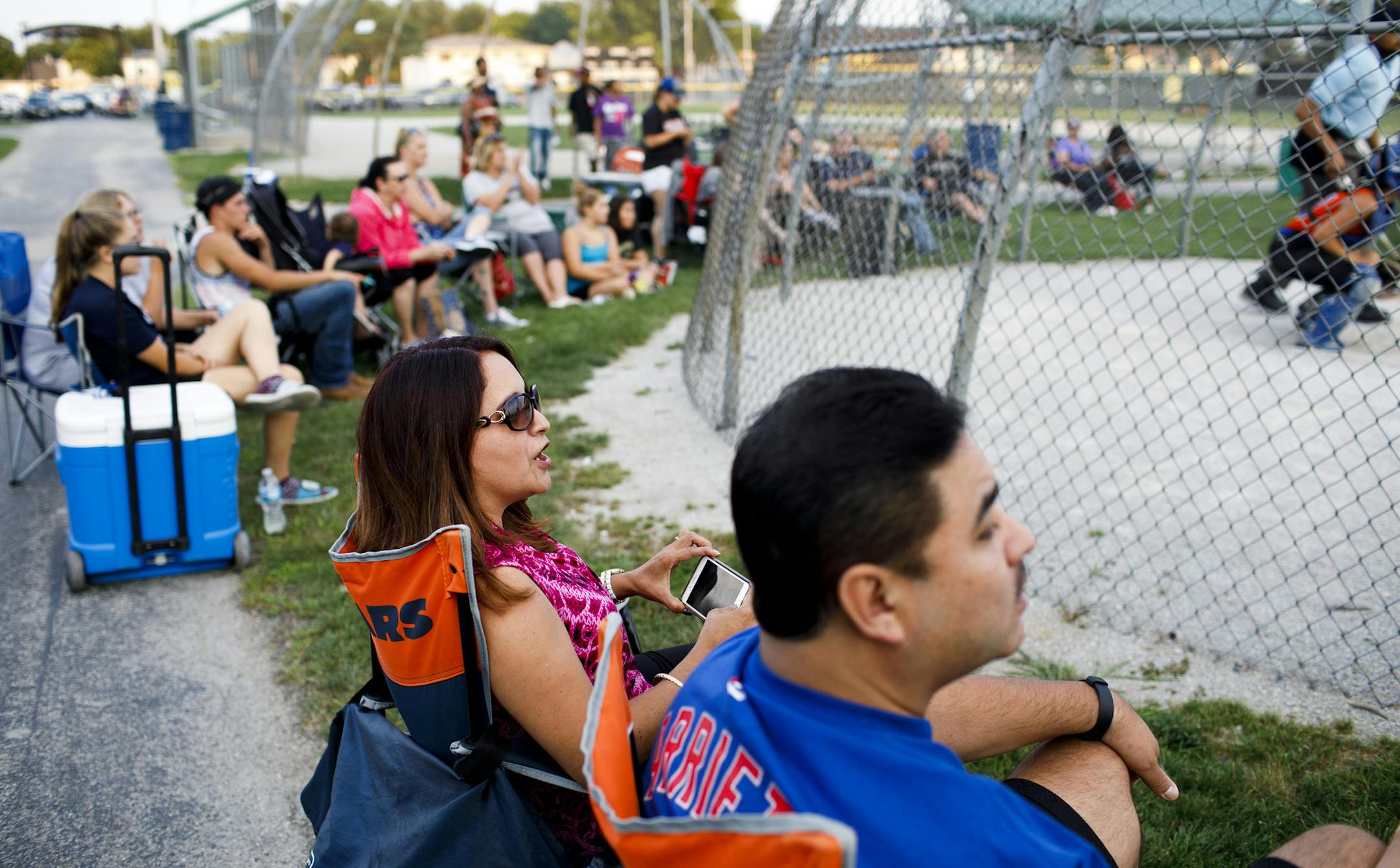 From left, Marilu Arce and her husband Raul Arce watch their daughter Alyssa Arce, 17, play softball at Bettenhausen Park on Tuesday, Aug. 1, 2017 in Tinley Park, Ill. Marilu Arce, an assistant controller in the corporate accounting department at the Chicago-based National Equity Fund, works from her Mokena home two days a week and says dropping her commute has given her time to take her daughters to after-school activities. (Armando L. Sanchez/Chicago Tribune/TNS)