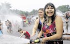 Shaniya Simpson, 14, right, is assisted by Akron Children's Hospital's Burn Camp counselor Caroline Kajder as she sprays fellow campers and others wit