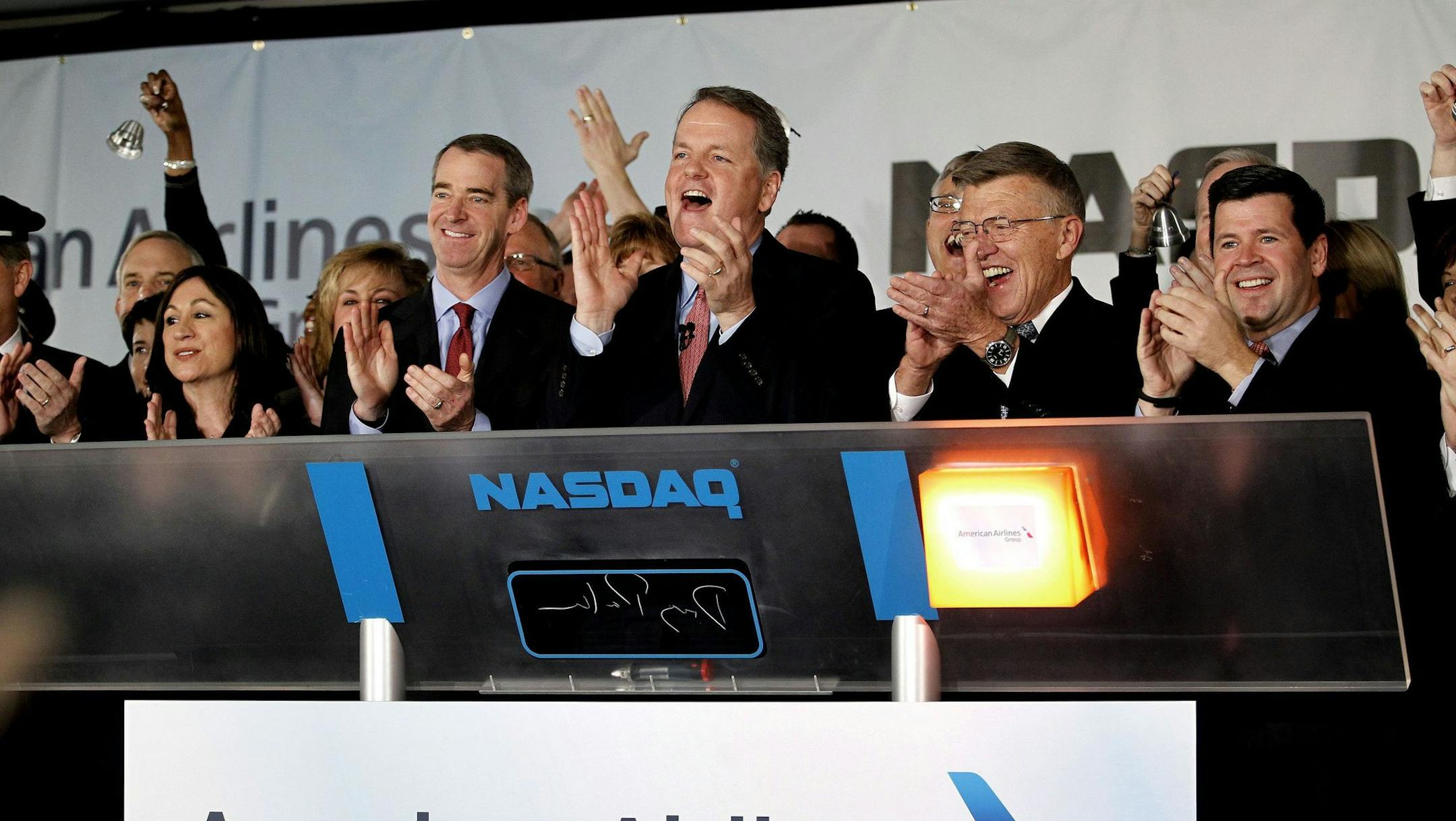 Former American CEOs Tom Horton (left), and Robert Crandall (right, glasses) applaud as new CEO Doug Parker (center) rings the NASDAQ bell, as hundreds of employees of the new American Airlines gather at the company's headquarters near DFW Airport to remotely ring the NASDAQ bell after the merger of American Airlines and US Airways, Monday, Dec. 9, 2013. (Paul Moseley/Fort Worth Star-Telegram/MCT)
