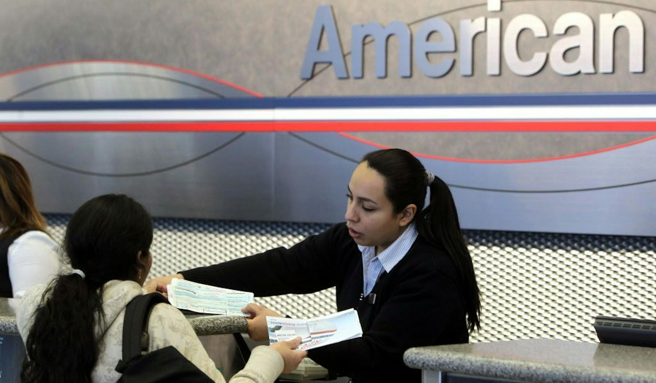 A ticket agent at the American Airlines terminal at O'Hare International Airport in Chicago, Illinois, discusses a ticket with a customer.