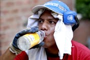 Daniel Garcia, 34, cools himself with water while wearing a t-shirt on his head to protect himself from a 90-degree heat while working his landscaping