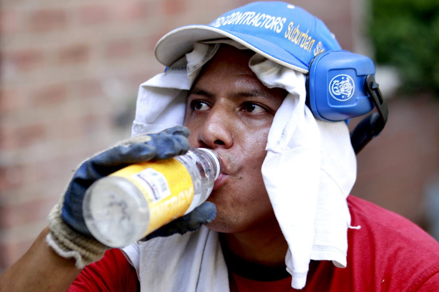 Daniel Garcia, 34, cools himself with water while wearing a t-shirt on his head to protect himself from a 90-degree heat while working his landscaping assignment at the Riverview Garden Apartments, Monday, in Passaic, N.J.