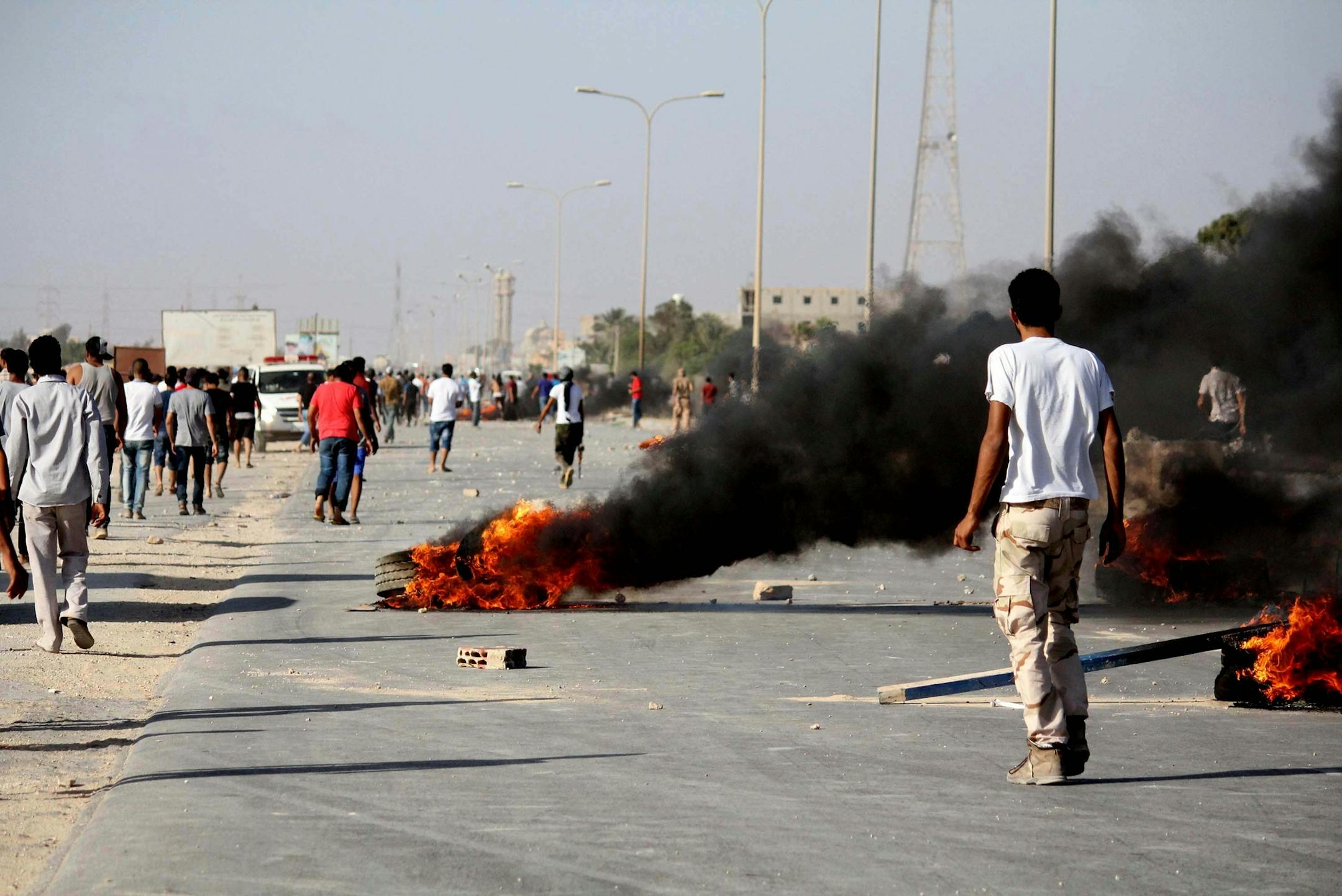 In this Saturday, June 8, 2013 photo, Libyans are seen during fighting outside the office of the Libya Shield pro-government militia in Benghazi, Libya. The violence which left dozens of people dead broke out Saturday when protesters stormed a base belonging to Libya Shield, a grouping of pro-government militias tasked with maintaining security. The protesters were demanding militias leave their camp and submit to the full authority of Libya's security forces. (AP Photo) ORG XMIT: MIN20130610150