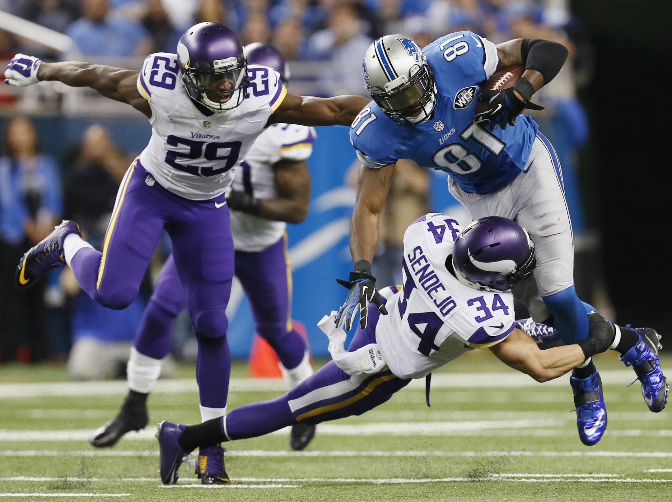 Detroit Lions wide receiver Calvin Johnson (81) is tackled by Minnesota Vikings free safety Andrew Sendejo (34) as cornerback Xavier Rhodes (29) closes in during the second half of an NFL football game at Ford Field in Detroit, Sunday, Dec. 14, 2014. (AP Photo/Paul Sancya)