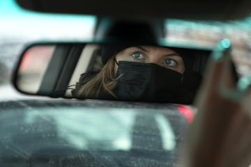 Kirsten DeHaven, who was assaulted and carjacked in January, adjusts the mirror in their car as they sat for a portrait Saturday, Feb. 12, 2022 in sou