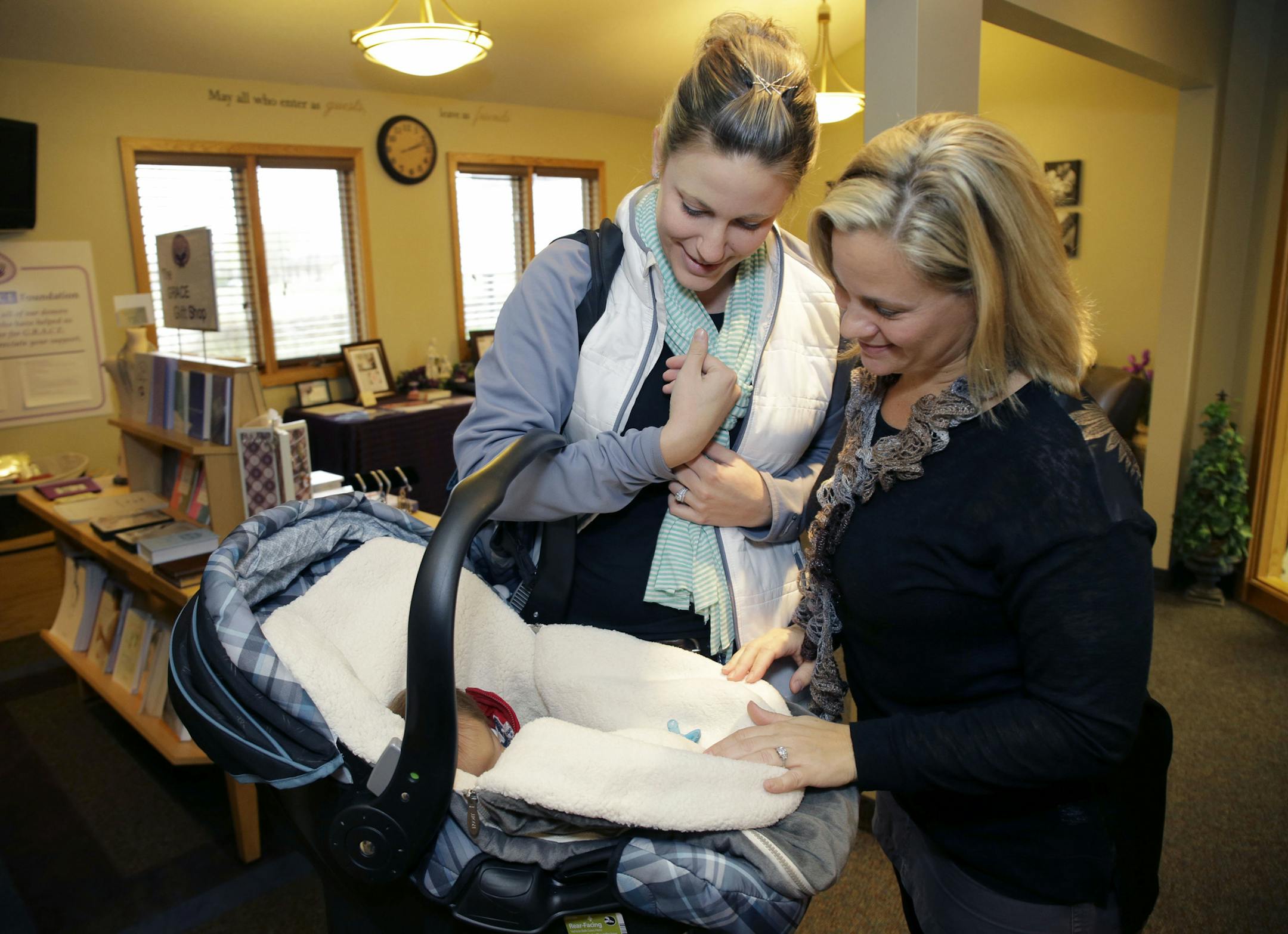 Assignment ID: 20031662A After her first child was stillborn in 2002, Candy McVicar vowed to turn her mourning into something positive. She founded the Missing Grace Foundation which has since become a national resource for parents who have experienced infant loss. McVicar, right, says goodbye to new mom Hallie Hoppe and her three week old son, Hudson, at the foundation in Rogers, Monday, Nov. 4, 2013. (Photo/Ann Heisenfelt)