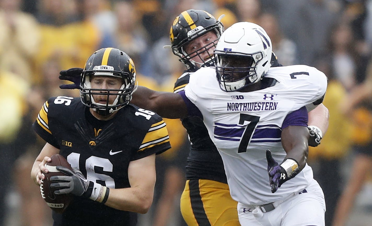 Iowa quarterback C.J. Beathard (16) runs from Northwestern defensive lineman Ifeadi Odenigbo (7) during the second half of an NCAA college football game, Saturday, Oct. 1, 2016, in Iowa City, Iowa. Northwestern won 38-31. (AP Photo/Charlie Neibergall)