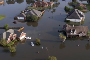 In this aerial photo, homes sit in floodwaters caused Tropical Storm Harvey in Port Arthur, Texas, Friday, Sept. 1, 2017. Port Arthur's major roads we