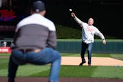 Former TV broadcaster Dick Bremer throws out the ceremonial first pitch to former Twins star Joe Mauer, a Hall of Fame-elect catcher.