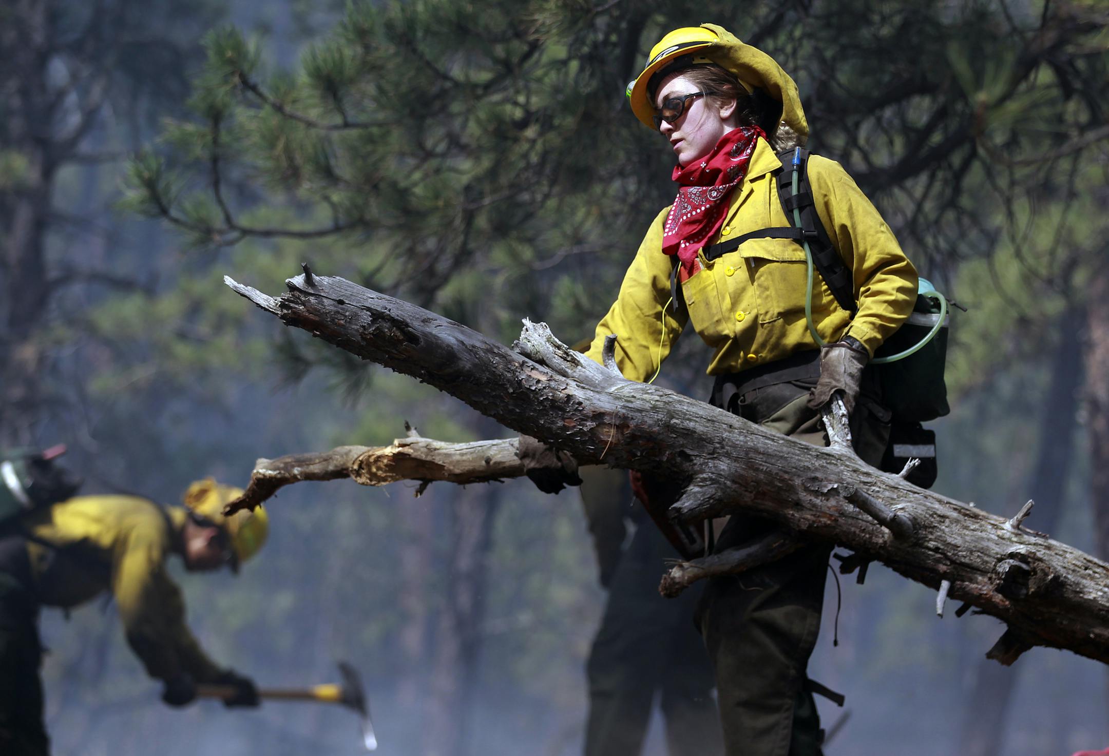 Samantha Marison, an AmeriCorps volunteer firefighter, removed wood to help contain a spot fire in an evacuated area of forest, ranches and residences in Colorado earlier this month.