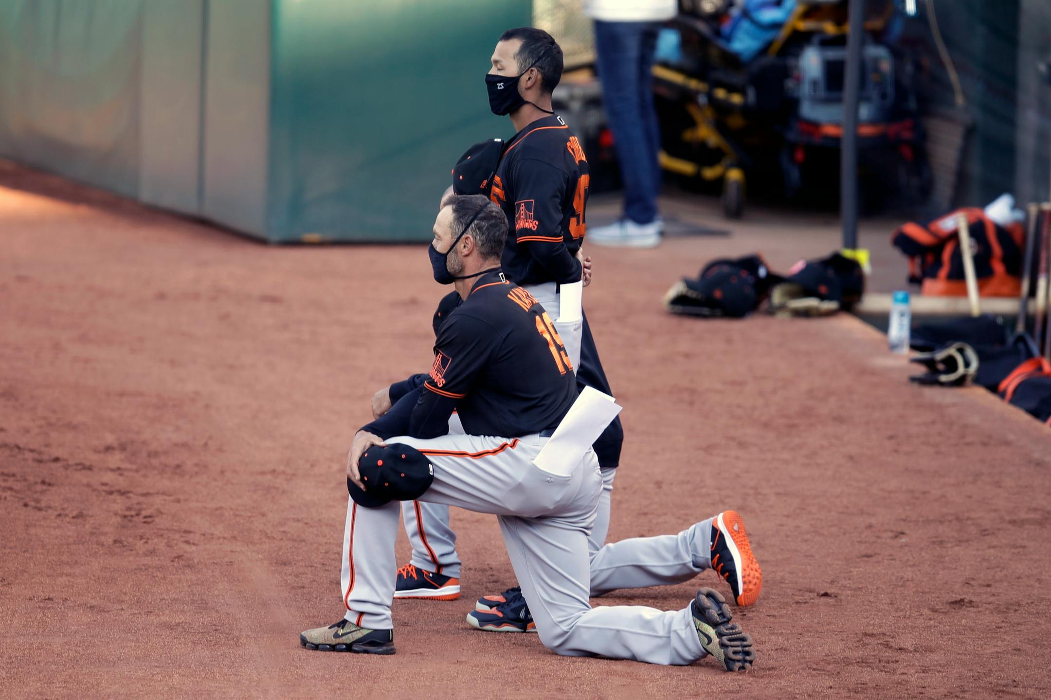 San Francisco Giants' manager Gabe Kapler kneels during the national anthem prior to an exhibition game against the Oakland Athletics
