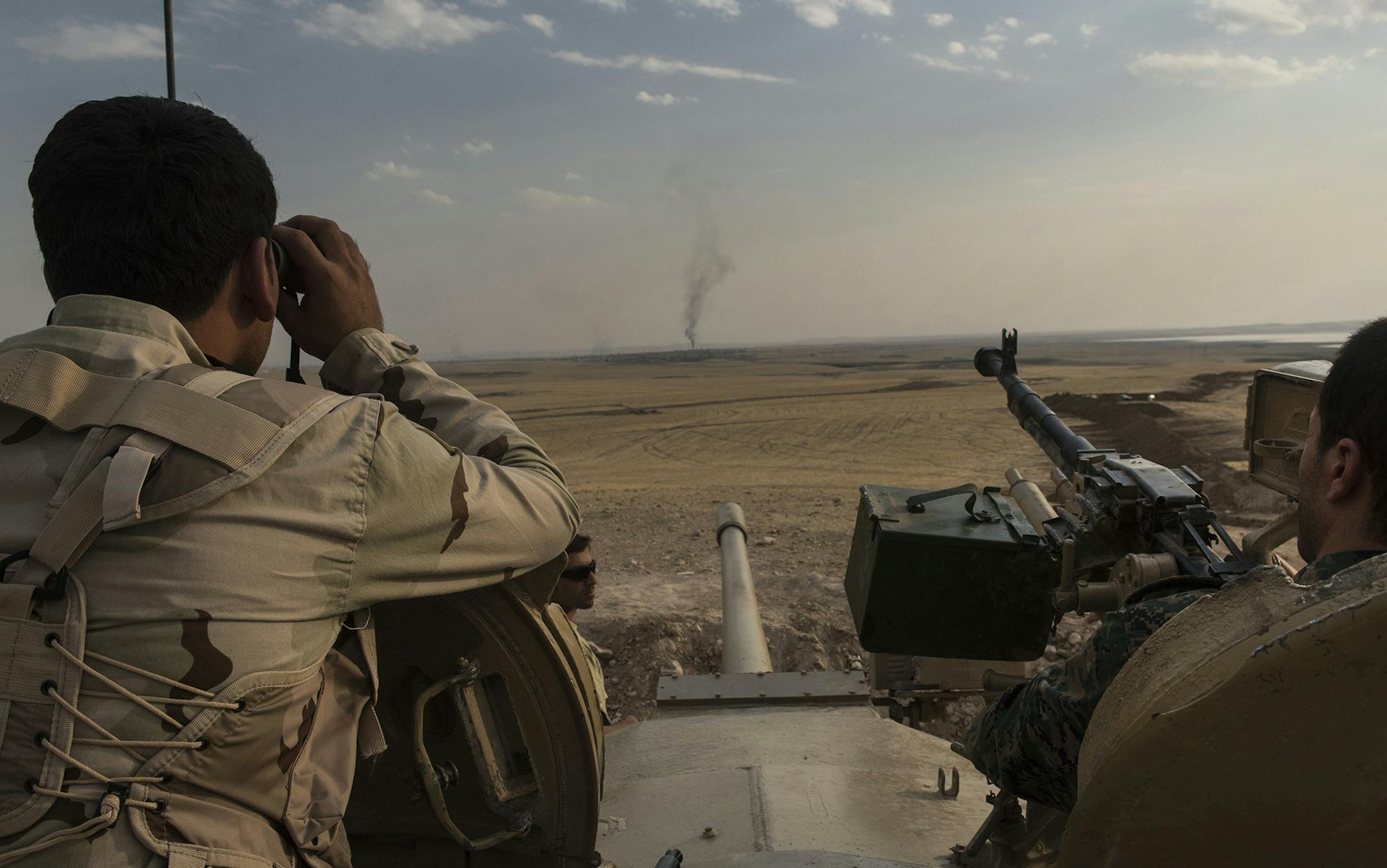 Kurdish peshmerga fighters watch smoke from American airstrikes rise from the village of Resala at an overwatch position near the Mosul Dam in Northern Iraq, Aug. 18, 2014. Kurdish and Iraqi forces took control of the main dam compound Monday, but fighting continued at the site of a separate dam, officials said. (Lynsey Addario/The New York Times) -- NO SALES ORG XMIT: MIN2014082112195136