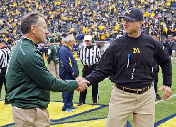 FILE - In this Oct. 17, 2015, file photo, Michigan State head coach Mark Dantonio shakes hands with Michigan head coach Jim Harbaugh on the Michigan S