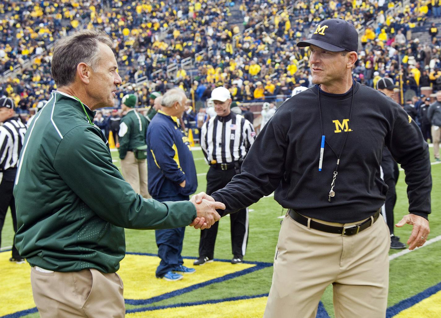 FILE - In this Oct. 17, 2015, file photo, Michigan State head coach Mark Dantonio shakes hands with Michigan head coach Jim Harbaugh on the Michigan Stadium field before an NCAA college football game in Ann Arbor, Mich. Sixth-ranked Michigan has won six straight and is in the top 10 for the first time this season. The Wolverines need to beat rival Michigan State this Saturday to keep the roll going. (AP Photo/Tony Ding, FIle)