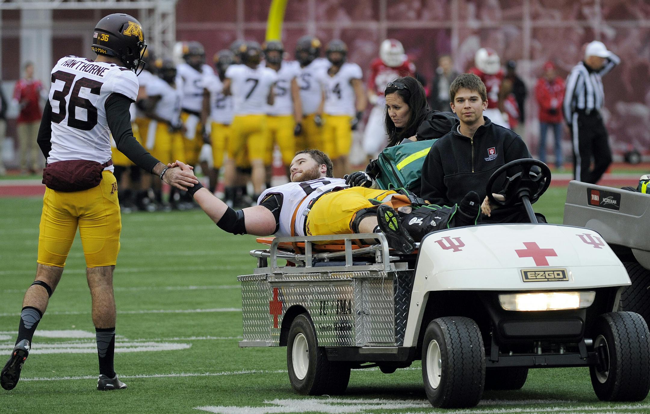 Minnesota's Chris Hawthorne, left, shakes Minnesota's Jon Christenson's hand as he is taken off the field after being injured during the first half of an NCAA college football game against Indiana in Bloomington, Ind., Saturday, Nov. 2, 2013. (AP Photo/ Alan Petersime)
