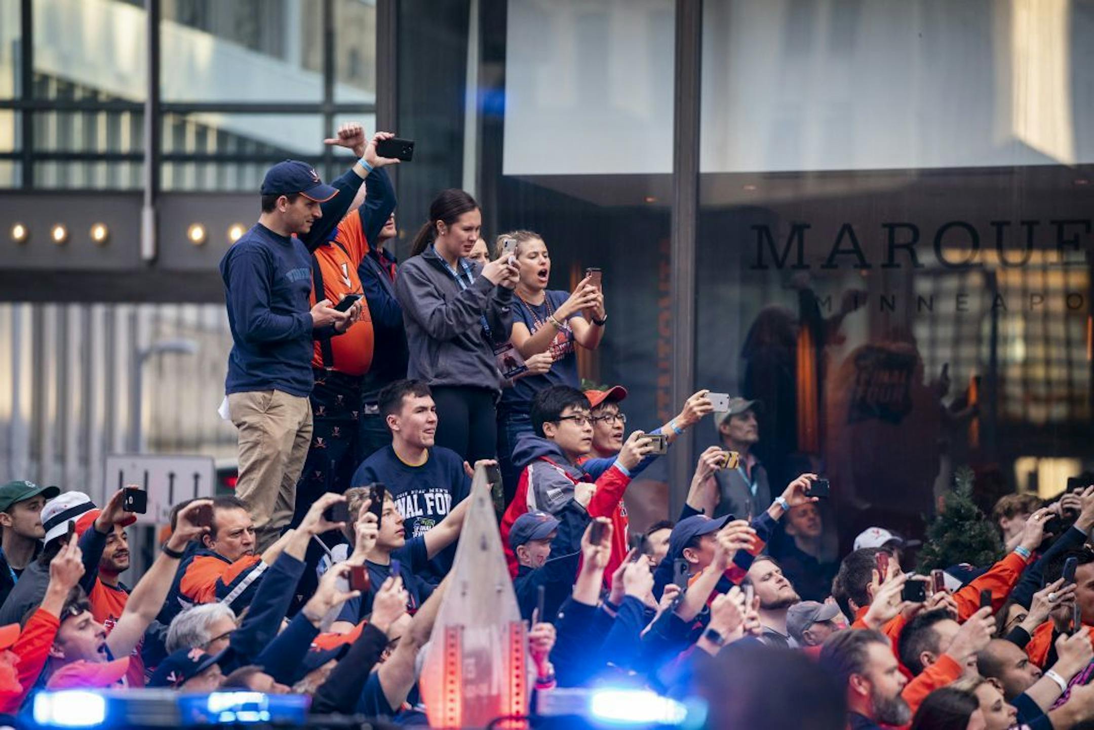 University of Virginia fans take photos and video outside the Marquette Hotel in downtown Minneapolis as their basketball team boards the bus.