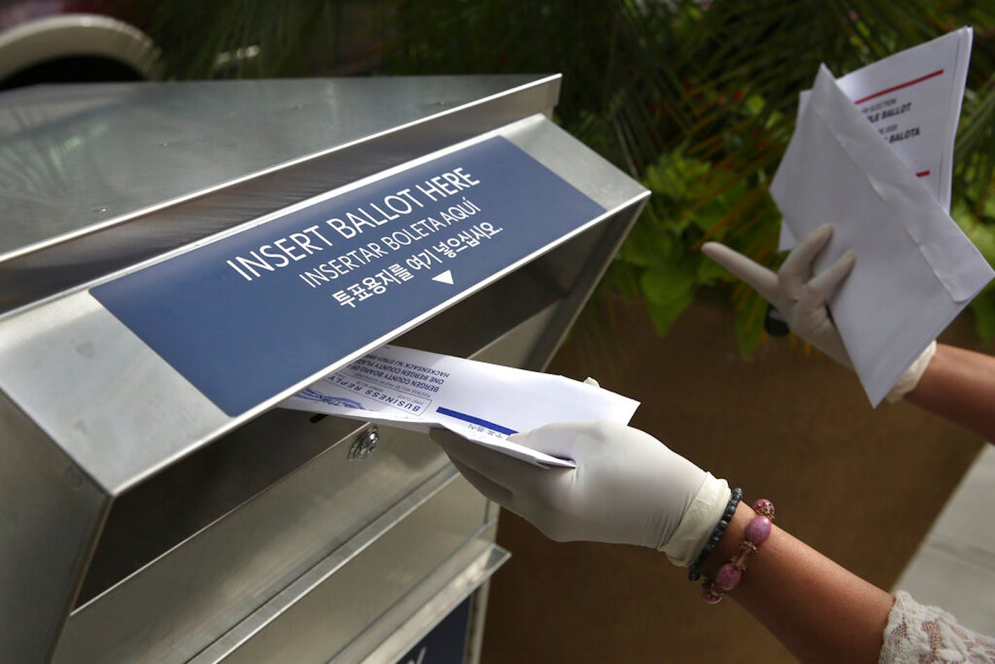 A woman drops off a mail-in ballot at a drop box in Hackensack, N.J.