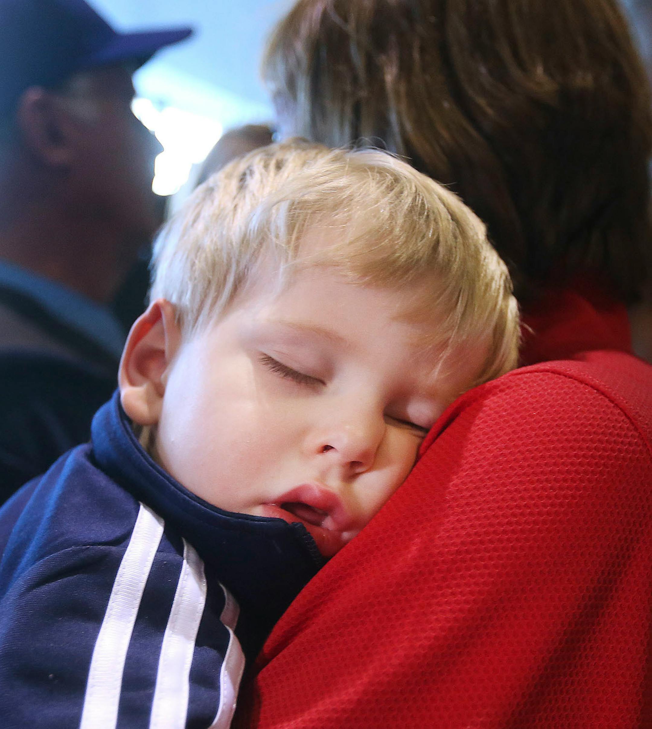 John Shuster's younger son Logan, 2, held by his grandmothers, Jackie Shuster, slept through the Duluth curling team's homecoming at the airport Monday evening. Bob King / rking@duluthnews.com