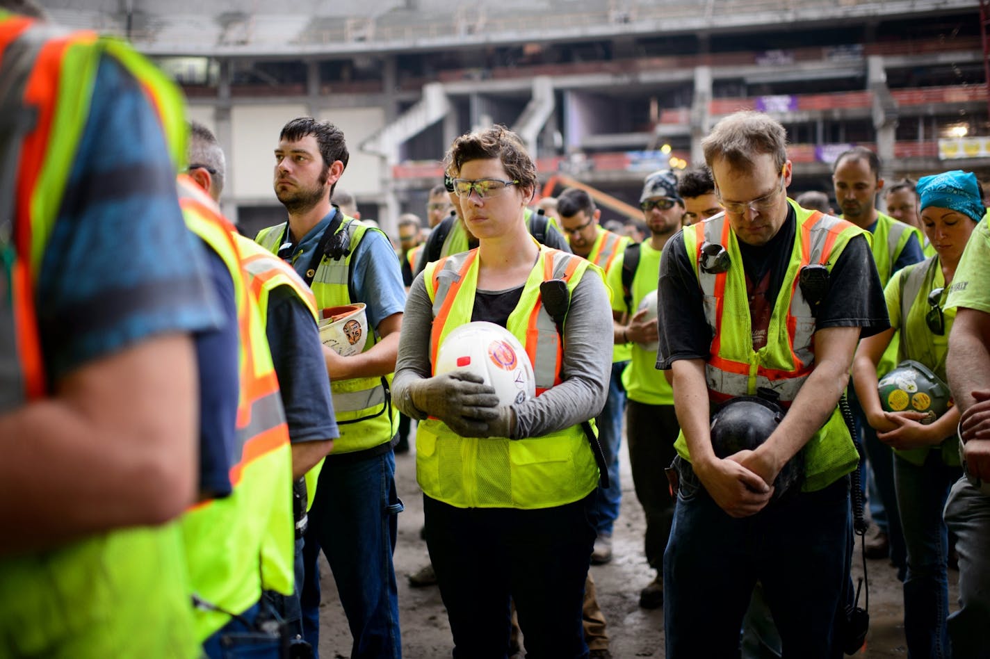 Stadium construction workers bowed their heads for a moment of silence for a fellow worker who was killed during construction.