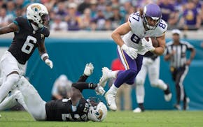 Vikings tight end T.J. Hockenson breaks a tackle by Jaguars linebacker Foyesade Oluokun on Sunday.