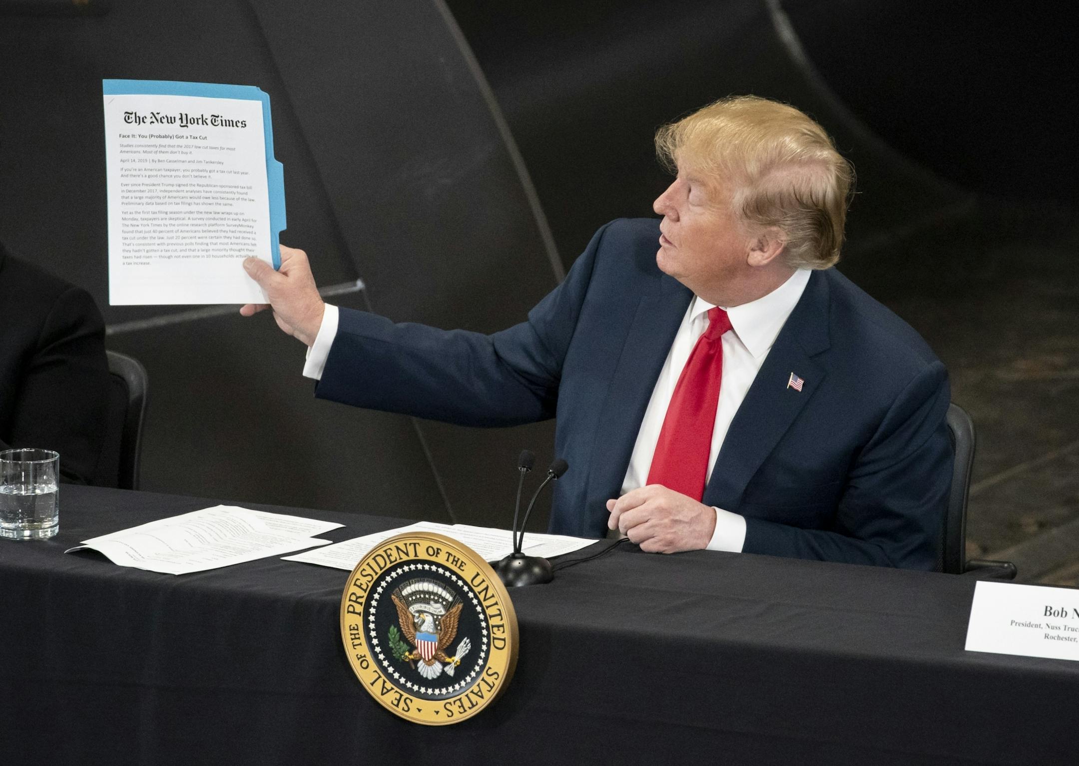 President Donald J. Trump help up a New York Times story as spoke at Nuss Truck and Equipment in Burnsville during a roundtable discussion on tax cuts and the U.S. economy in Burnsville, Minn., on Monday, April 15, 2019.