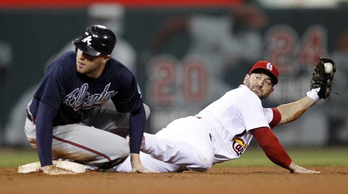 St. Louis Cardinals second baseman Nick Punto, right, holds up the ball after staying on-base and forcing out Atlanta Braves' Freddie Freeman, left, at second during the sixth inning of a baseball game on Saturday, Sept. 10, 2011, in St. Louis.