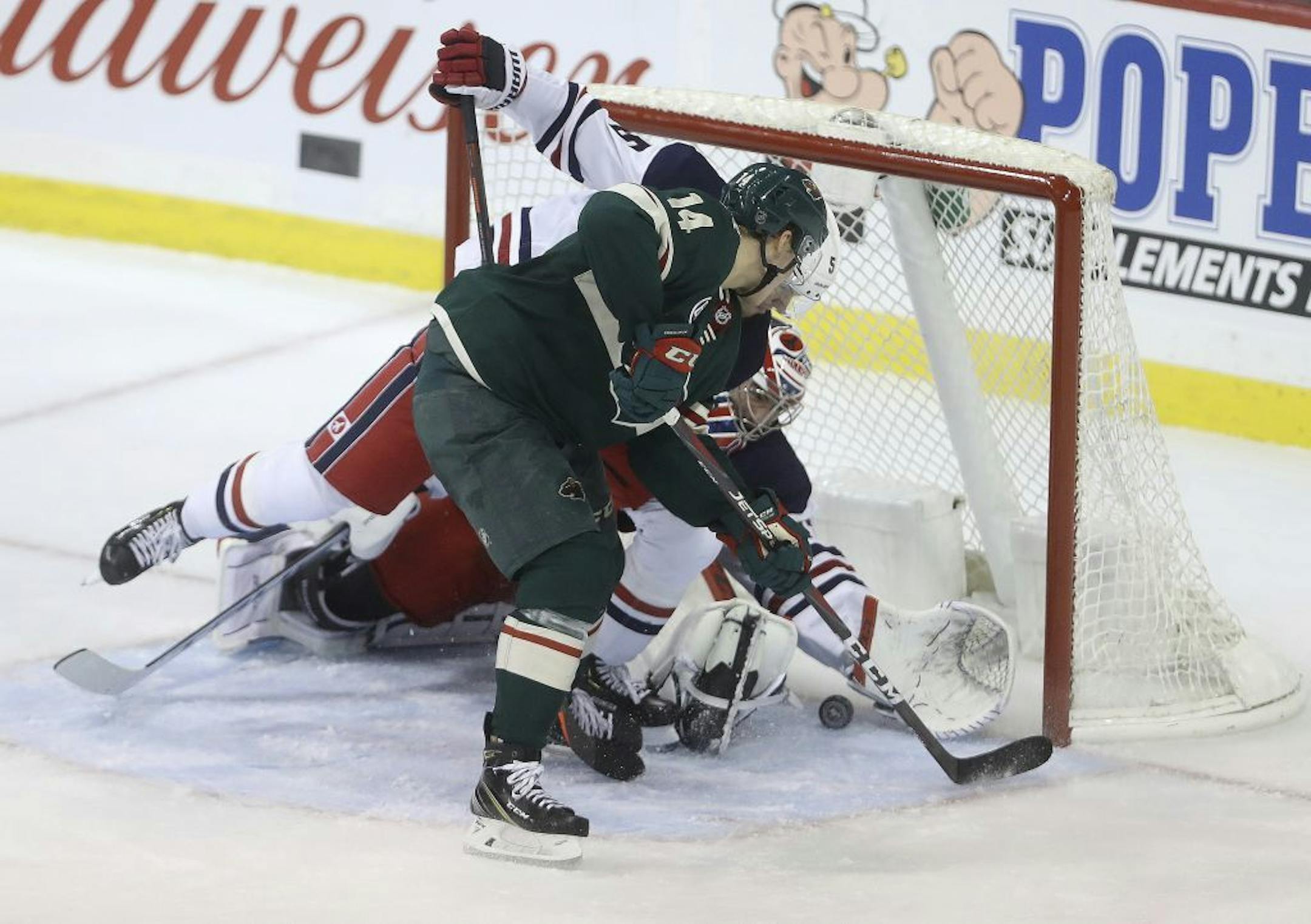 Minnesota Wild Joel Eriksson Ek (14) bangs the puck in past Winnipeg Jets' Dmitry Kulikov (5) and goaltender Connor Hellebuyck during the third period of an NHL hockey game Tuesday, Feb. 26, 2019, in Winnipeg, Manitoba.