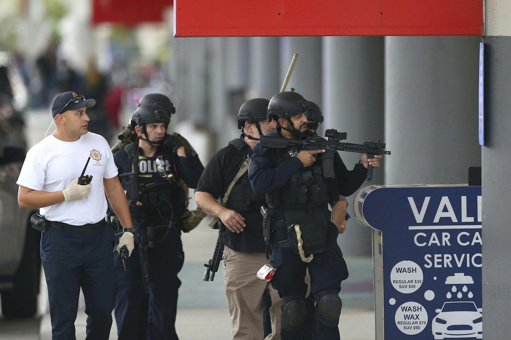 Law enforcement officers walk around Fort Lauderdale-Hollywood International Airport, Friday, Jan. 6, 2017, in Fort Lauderdale, Fla. A gunman opened fire in the baggage claim area at the airport Friday, killing several people and wounding others before being taken into custody in an attack that sent panicked passengers running out of the terminal and onto the tarmac, authorities said.