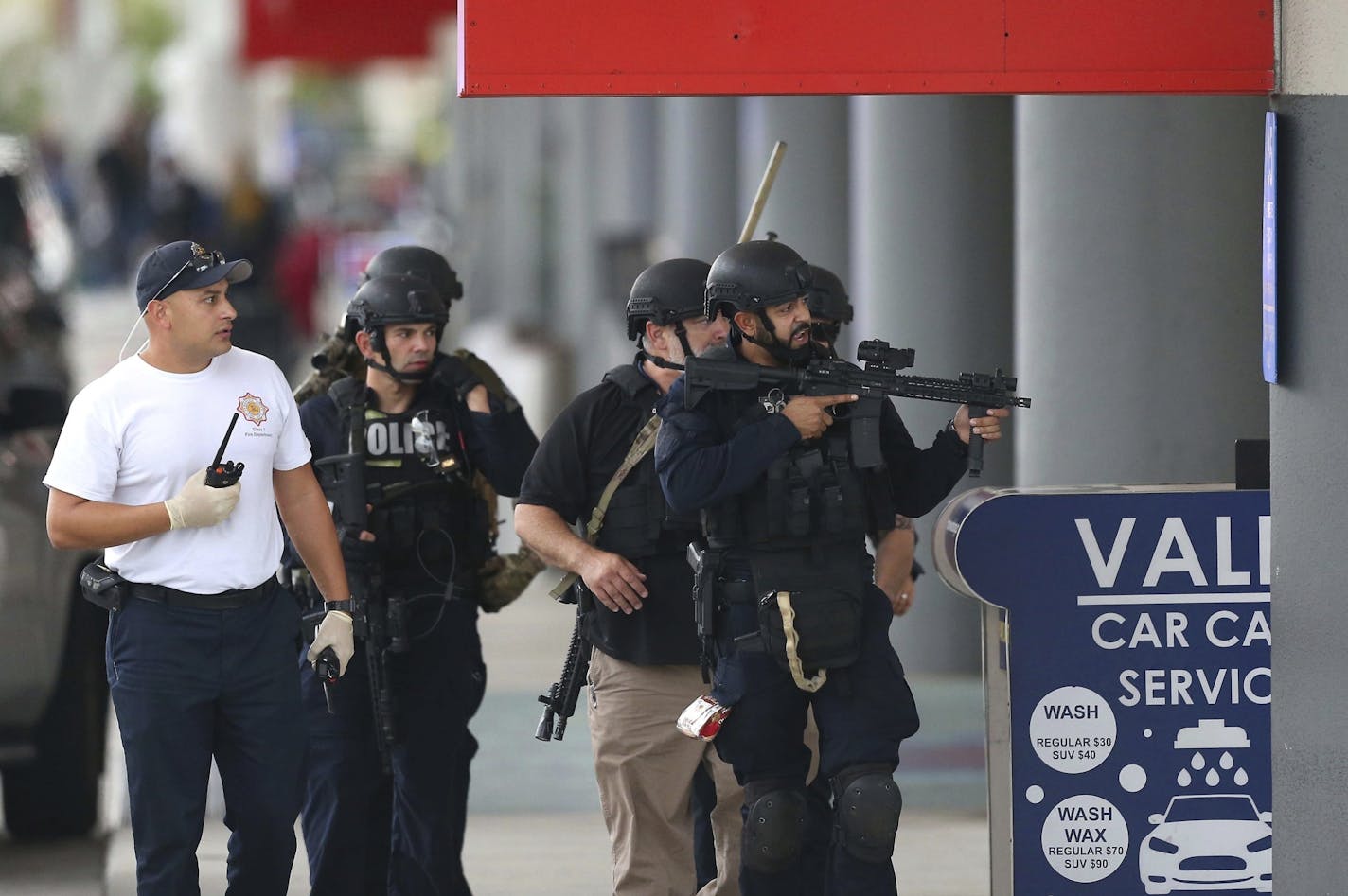 Law enforcement officers walk around Fort Lauderdale-Hollywood International Airport, Friday, Jan. 6, 2017, in Fort Lauderdale, Fla. A gunman opened fire in the baggage claim area at the airport Friday, killing several people and wounding others before being taken into custody in an attack that sent panicked passengers running out of the terminal and onto the tarmac, authorities said.