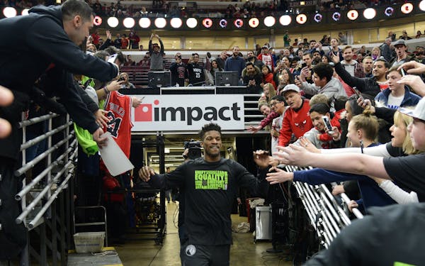 Former Chicago Bulls player Jimmy Butler, center, greets fans as he heads onto the court as a member of the Minnesota Timberwolves before an NBA baske