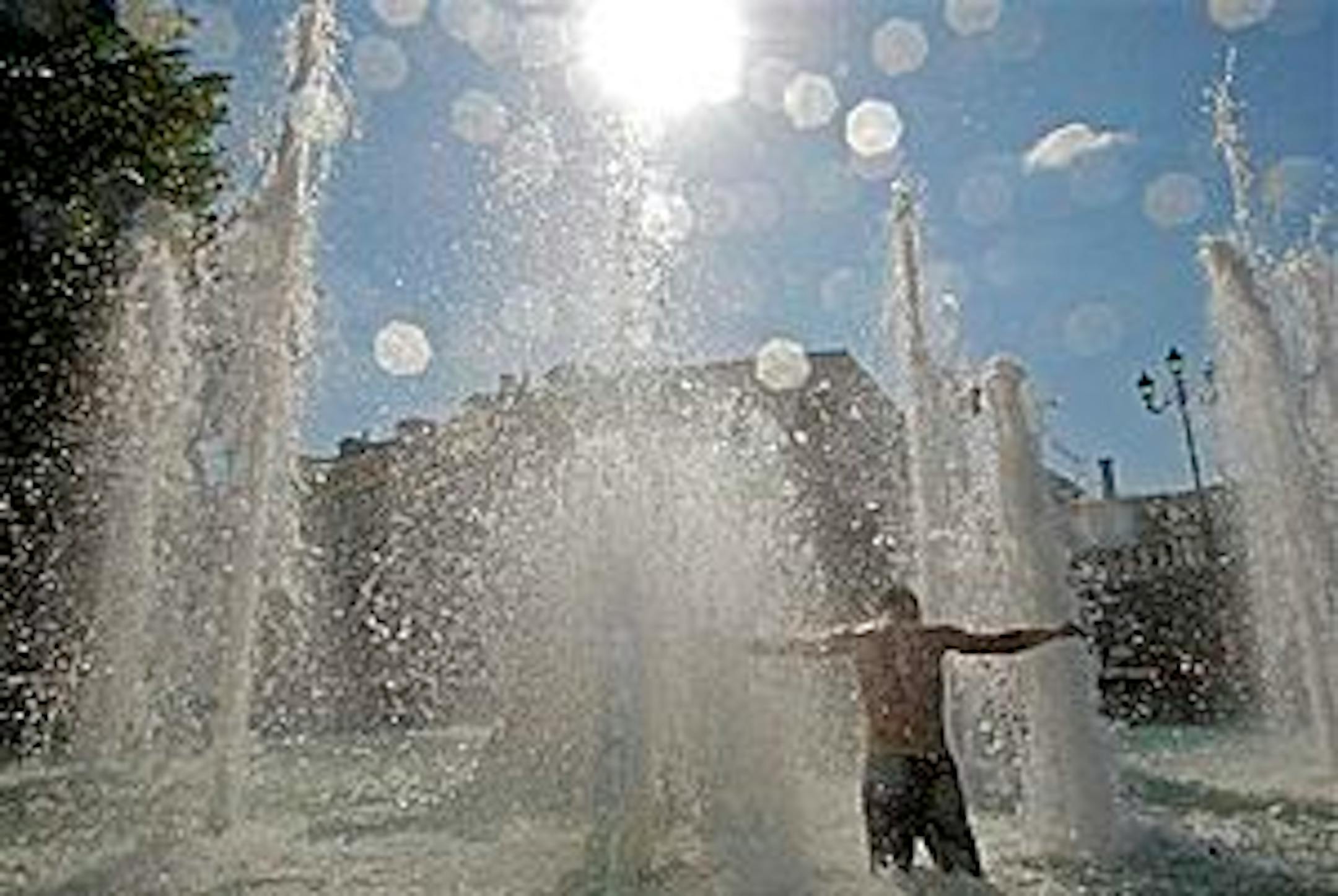 A man enjoys waterjets seeking coolness in a fountain at the Alexandrovsky Garden outside the Kremlin in Moscow, Tuesday, July 13, 2010. A heat wave hit the city with  temperatures going higher than 30 C (86 F). (AP Photo/Mikhail Metzel)