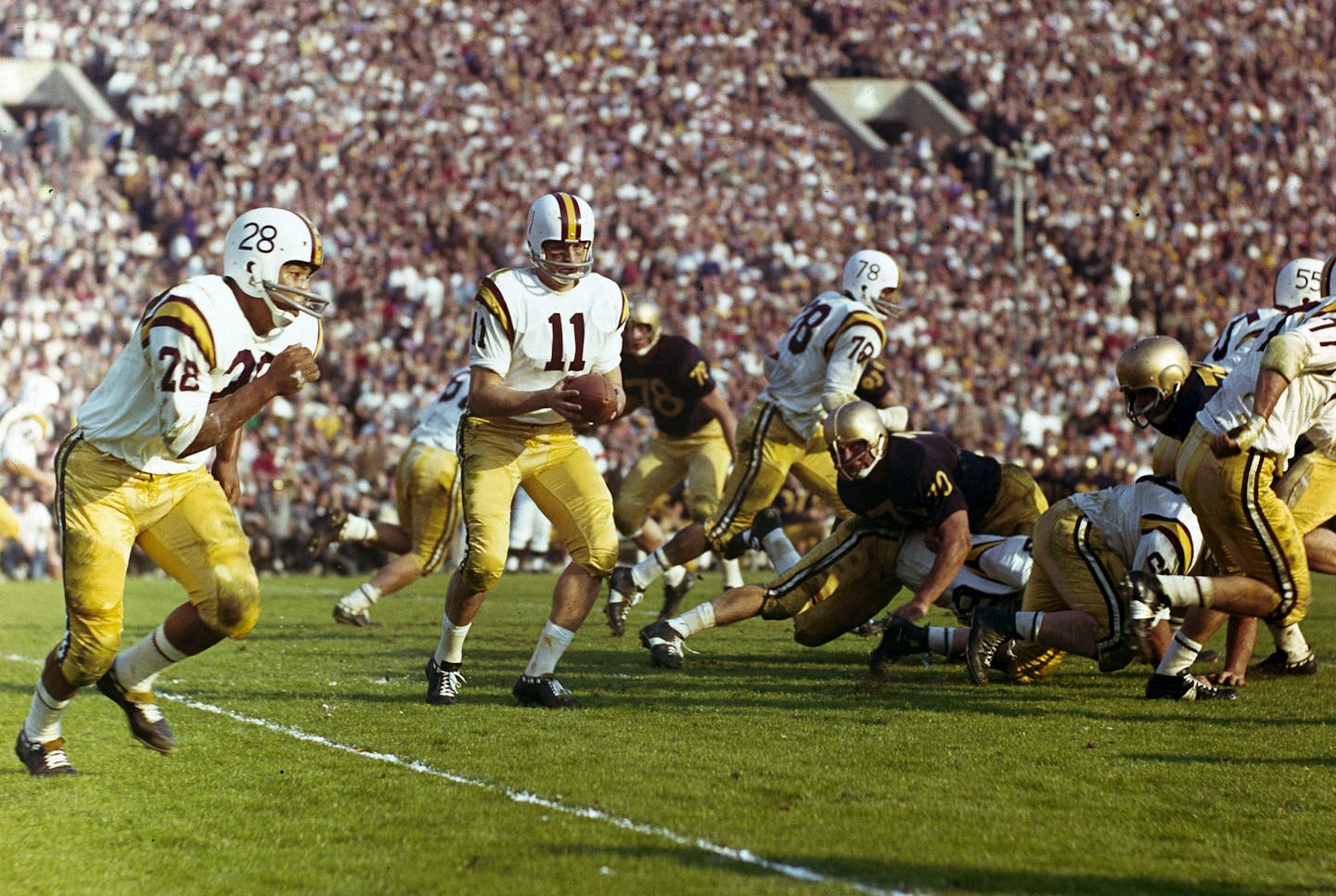 Quarterback Joseph Salem (11) of the University of Minnesota prepares to hand the ball off to running back William Munsey (28) during the Rose Bowl game against the University of Washington in Pasadena, Calif., Jan. 2, 1961. (AP Photo)