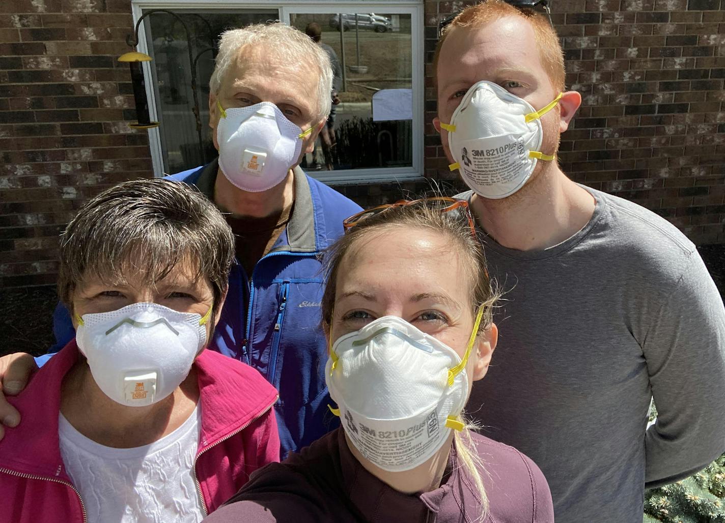 Steve and Julie Schmidt, with son and daughter-in-law Geoff and Rachael, gathered outside the window of Steve's father, Melvin Schmidt, at a Twin Cities nursing home.